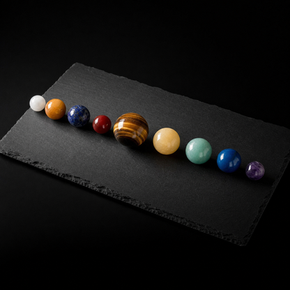Solar System Mineral Sphere Display — museum gallery editorial photograph on dark charcoal slate with spot lighting
