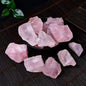 Overhead view of multiple raw rose quartz rough chunks in a dark bowl and scattered on a bamboo mat, soft pink color with waxy luster