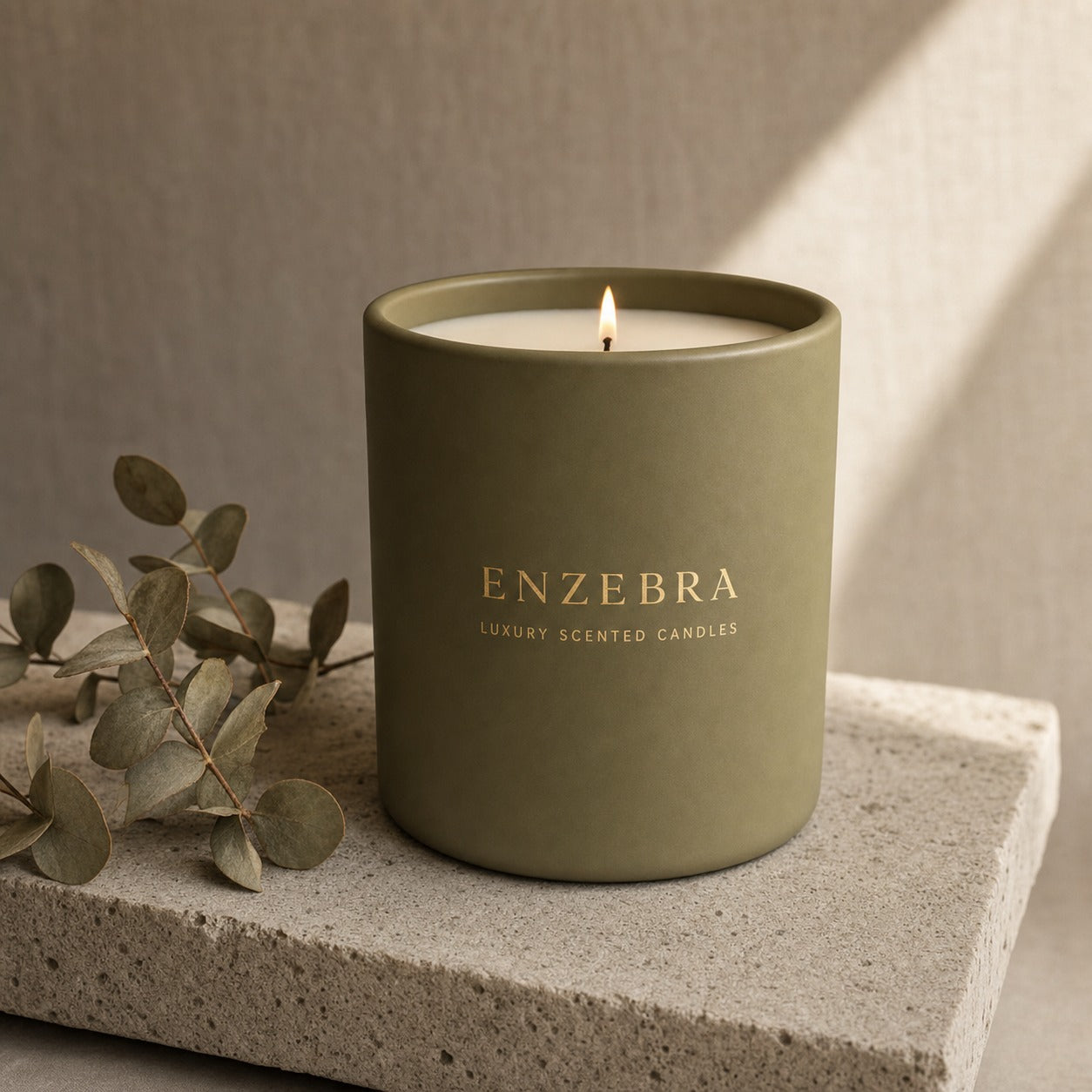 EnZebra Olive Green 12oz luxury scented candle — lit with eucalyptus on concrete