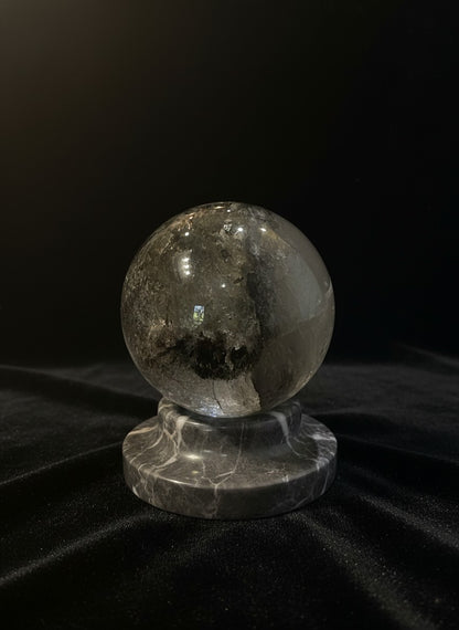 Zebra Industries, LLC collector grade garden quartz sphere with green mineral inclusions on a grey marble stand.