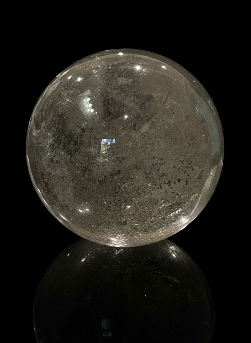 Zebra Industries, LLC large polished garden quartz crystal sphere with natural inclusions on a black background.