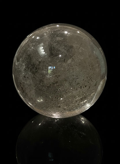 Zebra Industries, LLC large polished garden quartz crystal sphere with natural inclusions on a black background.