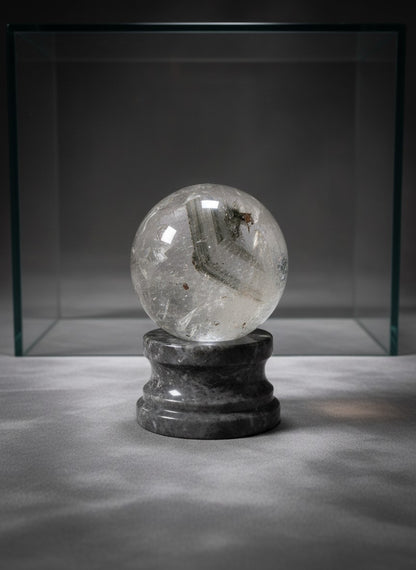 Zebra Industries, LLC collector grade garden quartz polished sphere with green mineral inclusions on a grey stone base.