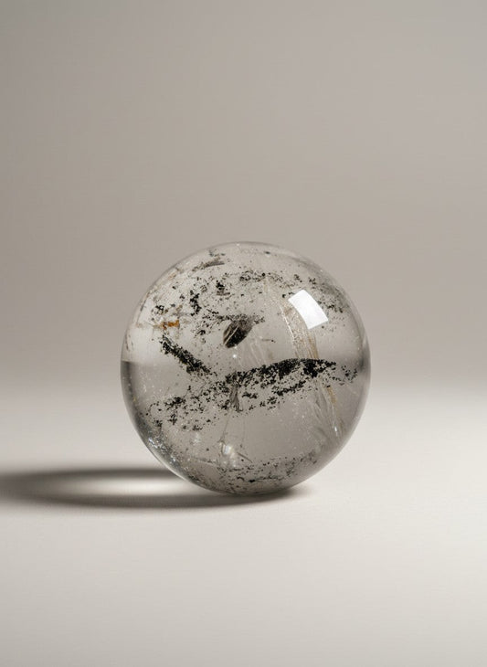 Zebra Industries, LLC collector grade garden quartz crystal sphere with black inclusions on a neutral background