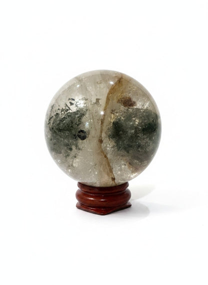 Zebra Industries, LLC garden quartz crystal sphere with natural green inclusions on a polished wooden display stand.