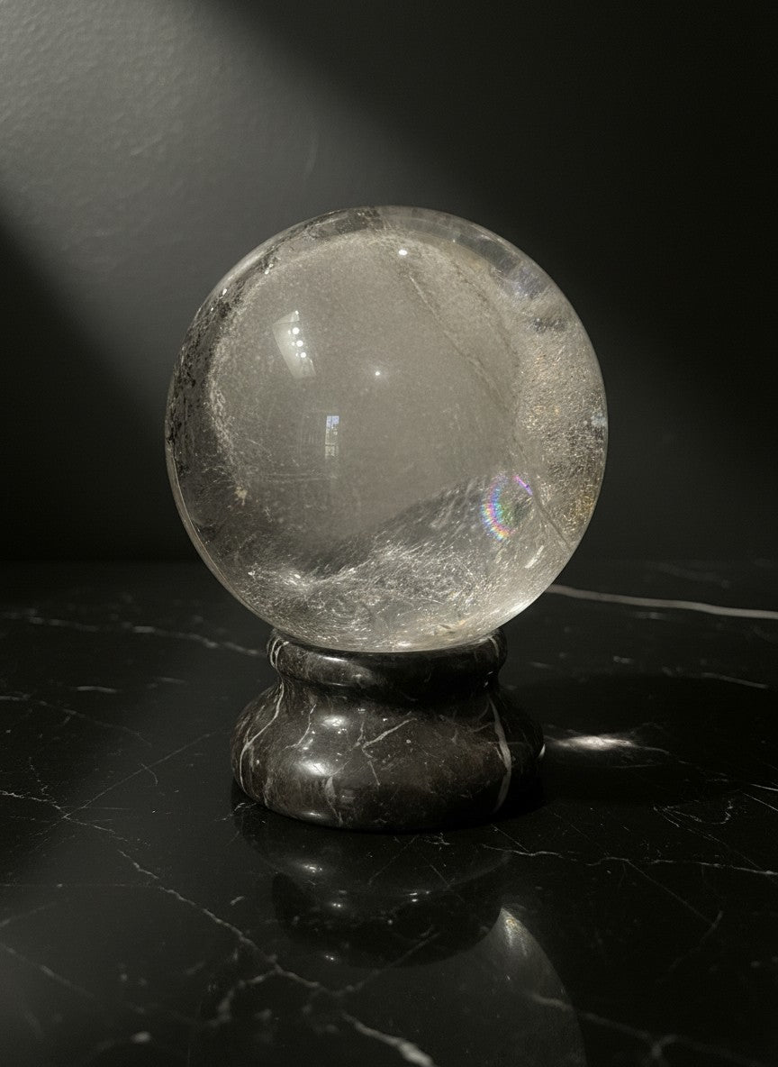 Zebra Industries, LLC large polished Garden Quartz sphere with internal inclusions on a black marble stand.