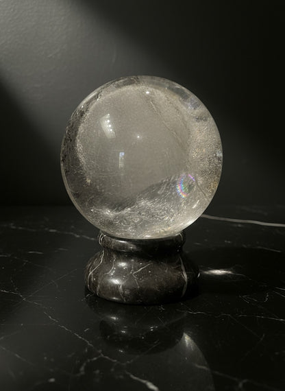 Zebra Industries, LLC large polished Garden Quartz sphere with internal inclusions on a black marble stand.
