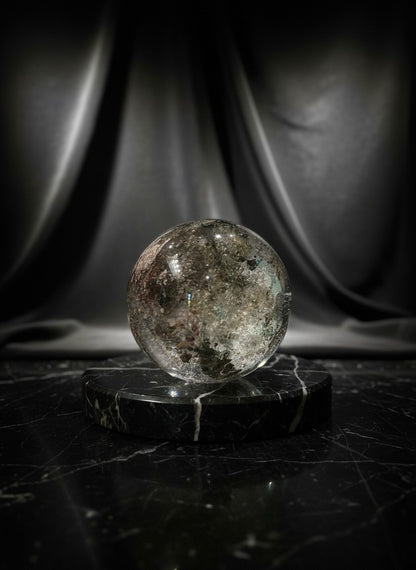 Zebra Industries, LLC collector grade garden quartz sphere with green mineral inclusions on a black marble base.