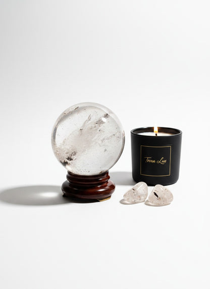 Zebra Industries, LLC garden quartz sphere on a wooden stand next to a lit black candle and two small quartz crystals.