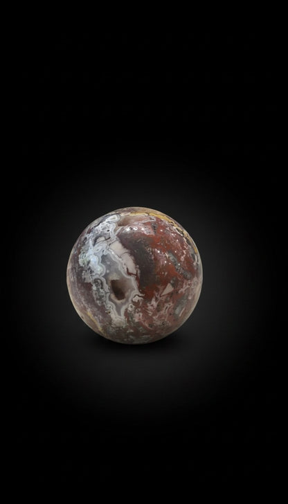 Zebra Industries, LLC Laguna Lace agate sphere with a natural druzy cavity and intricate red and white mineral patterns.