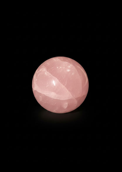 Zebra Industries, LLC polished rose quartz crystal sphere with natural inclusions on a black background